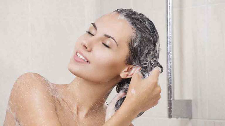 woman in shower washing hair with shampoo