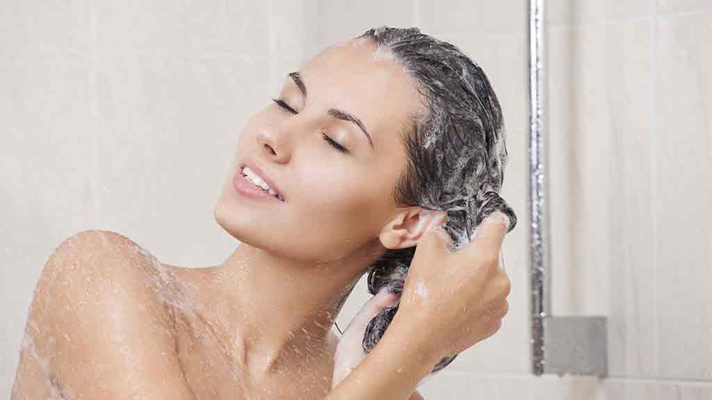 woman in shower washing hair with shampoo