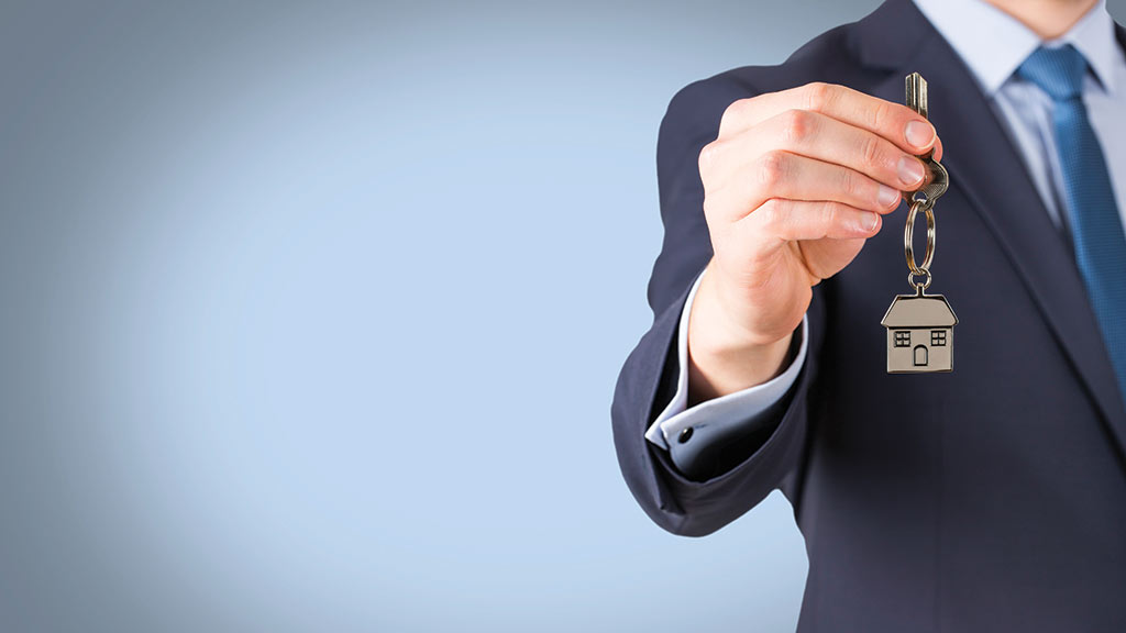 male real estate agent in suit holding house key