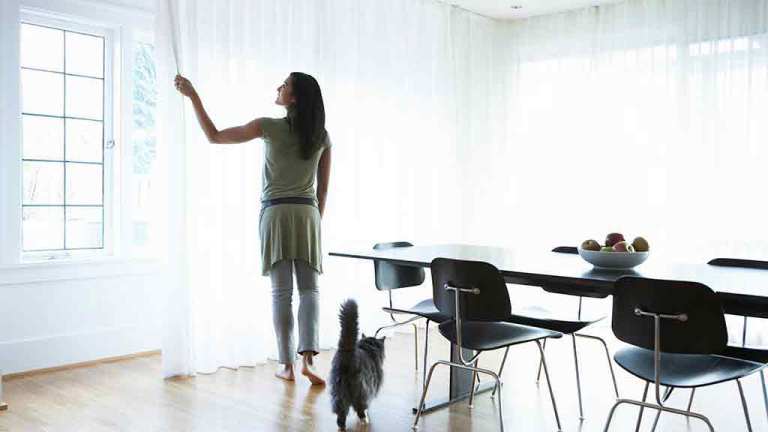woman draws curtains in bright room