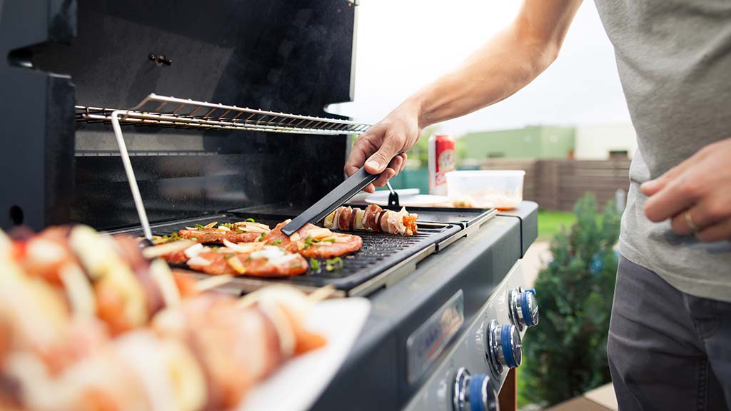 man using bbq with tongs