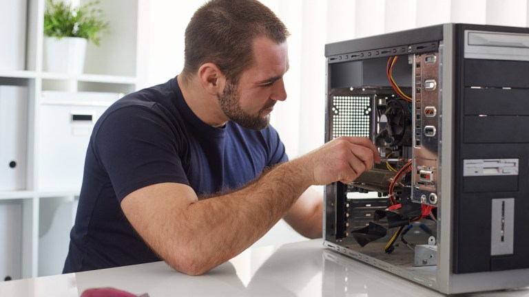 a man sitting at a bench building his own computer