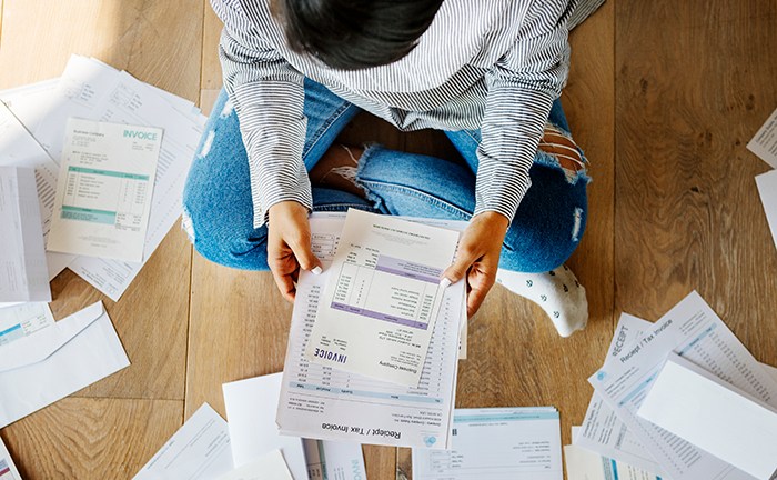 person_sitting_on_floor_looking_at_several_bills_and_invoices