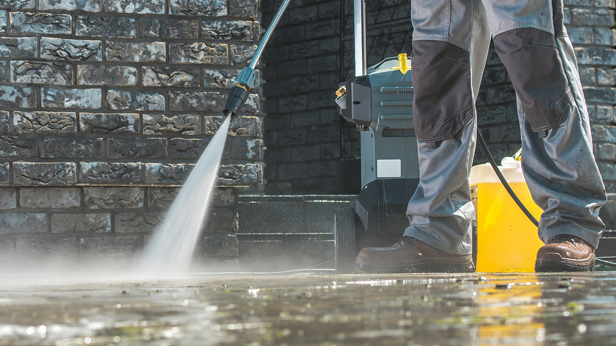 person_testing_pressure_washer_on_driveway