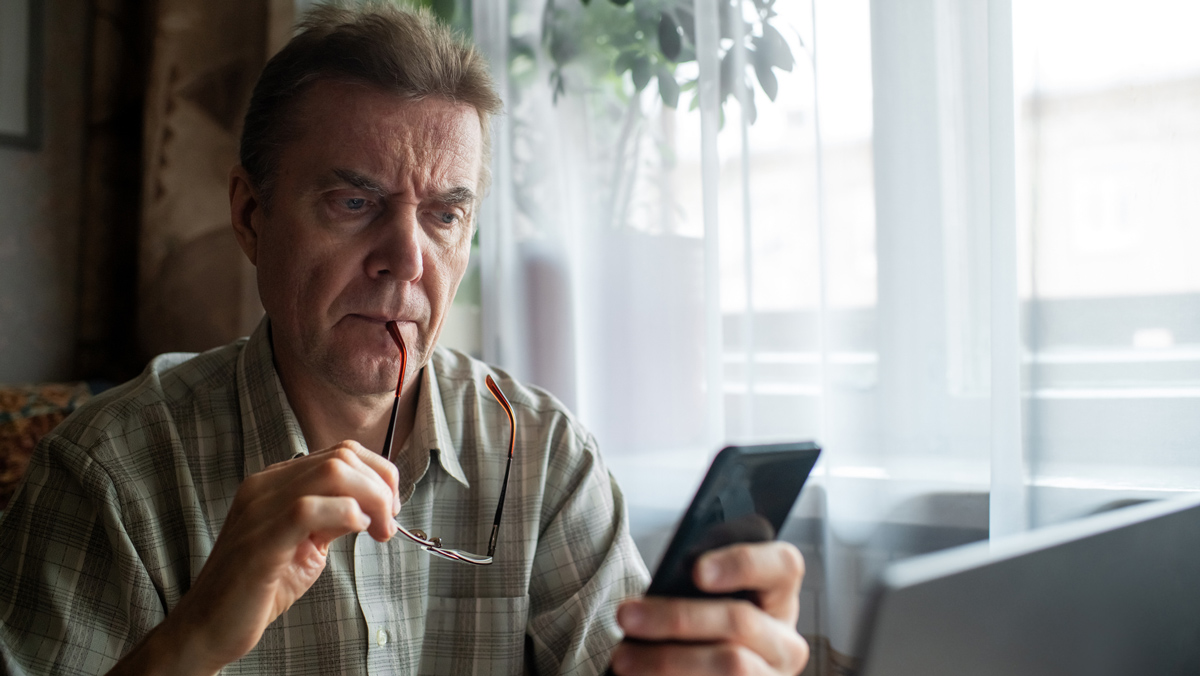 man_looking_at_phone_banking_scam_lead