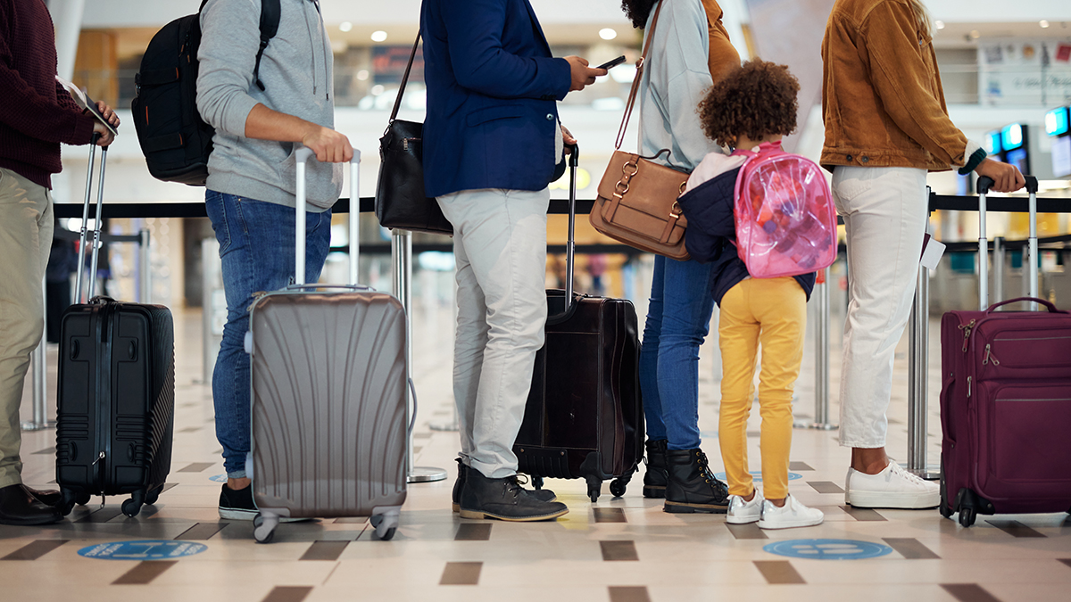 queue of passengers with their luggage at airport