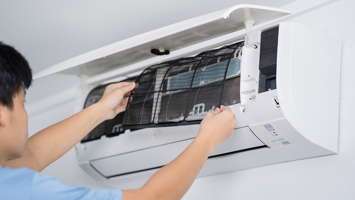 person removing air conditioner filter to clean
