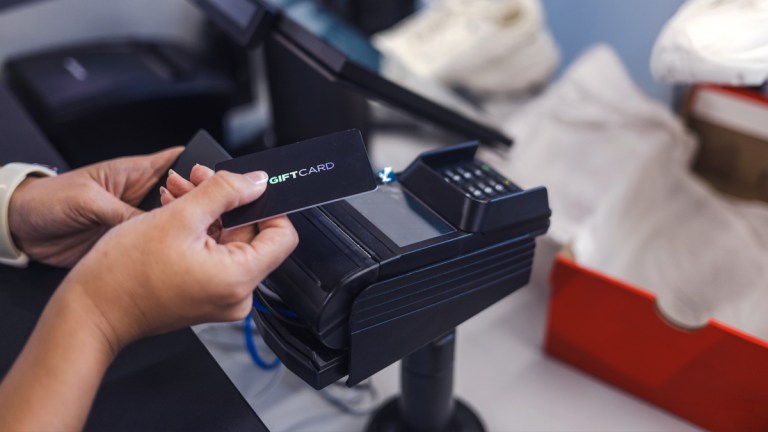person using gift card at register in shoe store