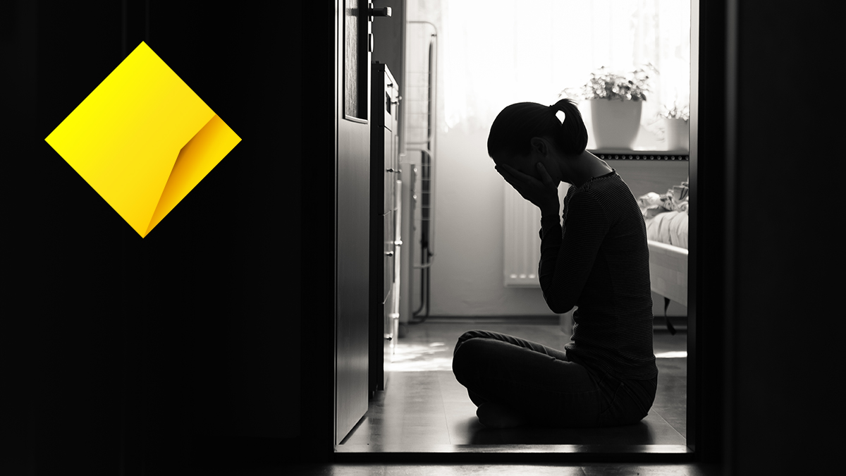 upset woman on bedroom floor and commonwealth bank logo