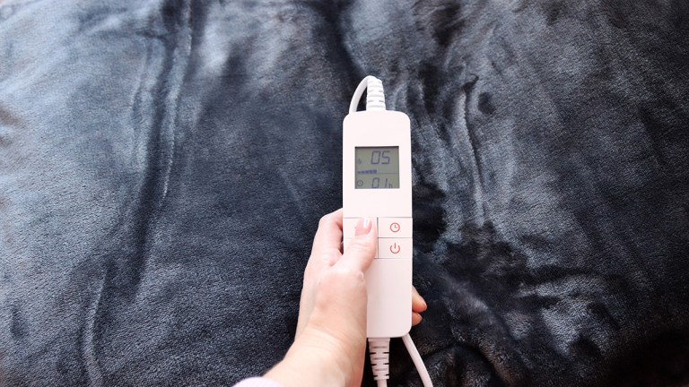 person adjusting controller of heated throw