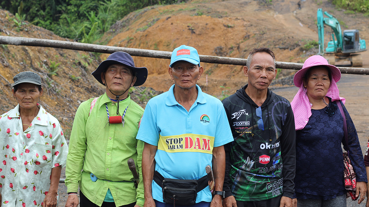 Five indigenous Penan villagers stand before a logging blockade.
